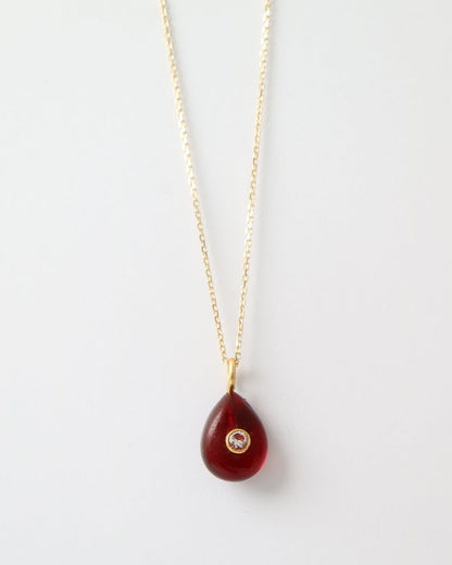 Garnet Glow Pendant featuring a deep red teardrop gemstone with a bezel-set cubic clear quartz and gold plated sterling silver bail on a white background.