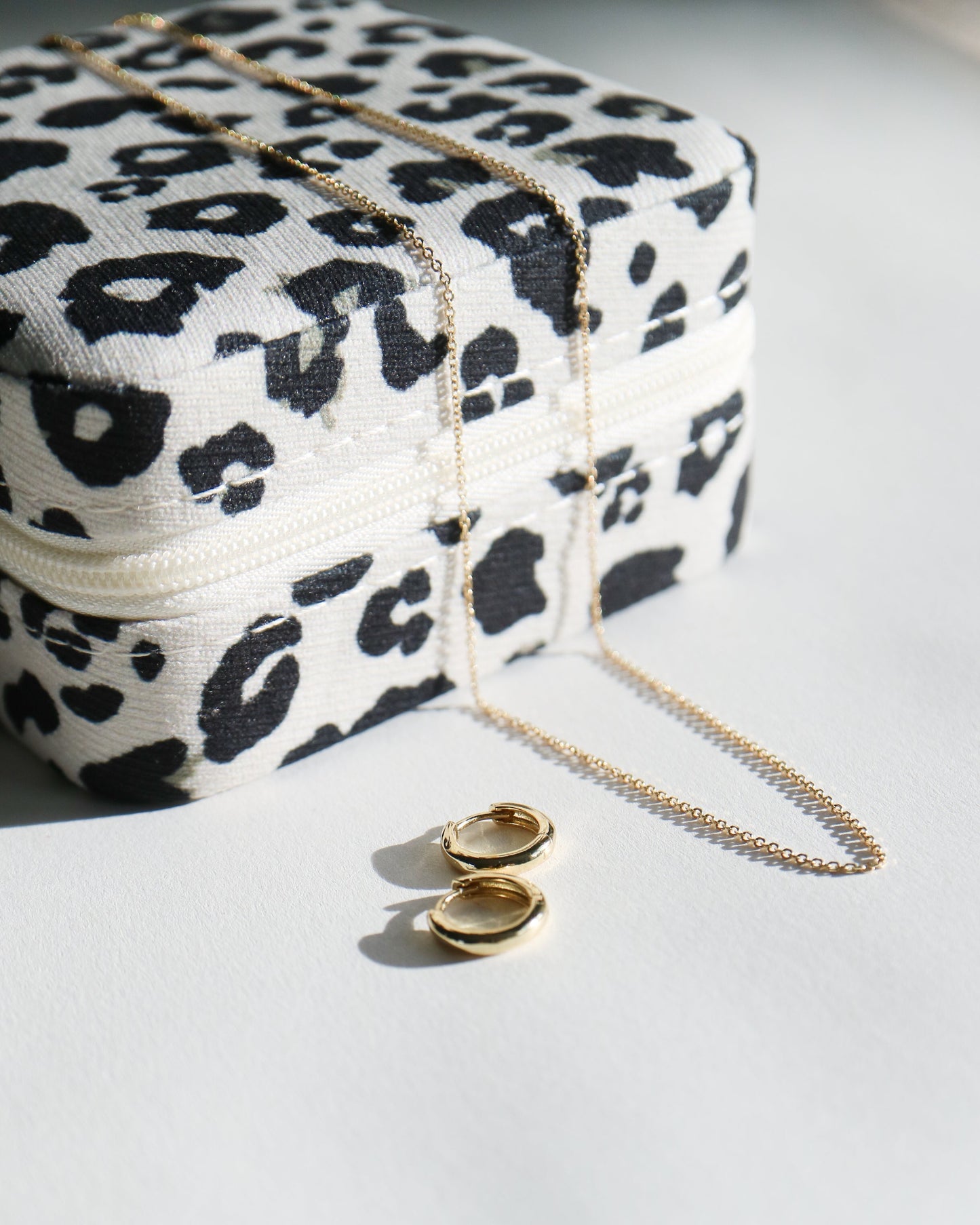 Leopard print jewelry box with gold necklace and earrings on a white surface