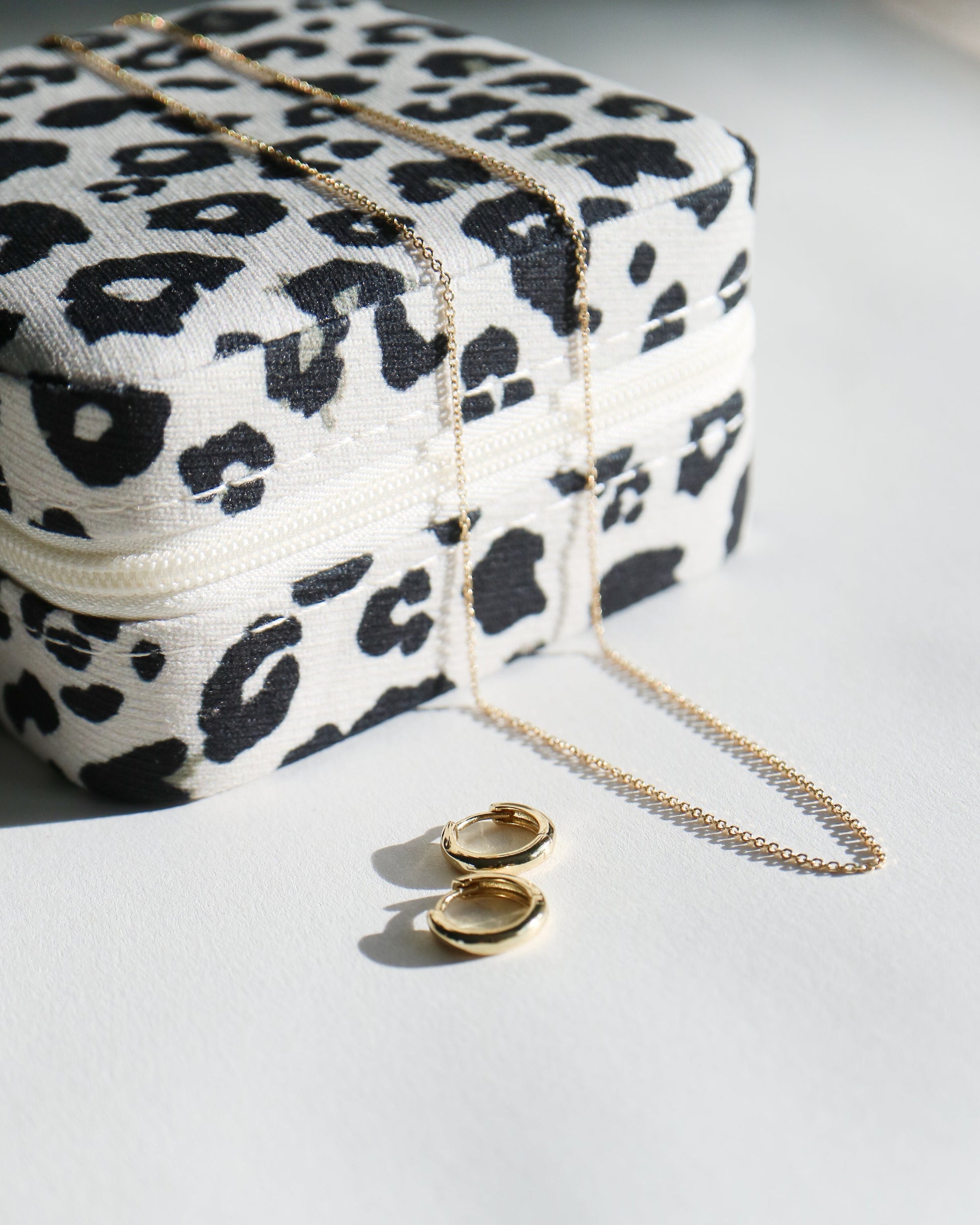 Leopard print jewelry box with gold necklace and earrings on a white surface