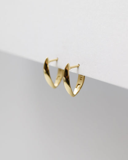 Gold hoop earrings on a light gray surface