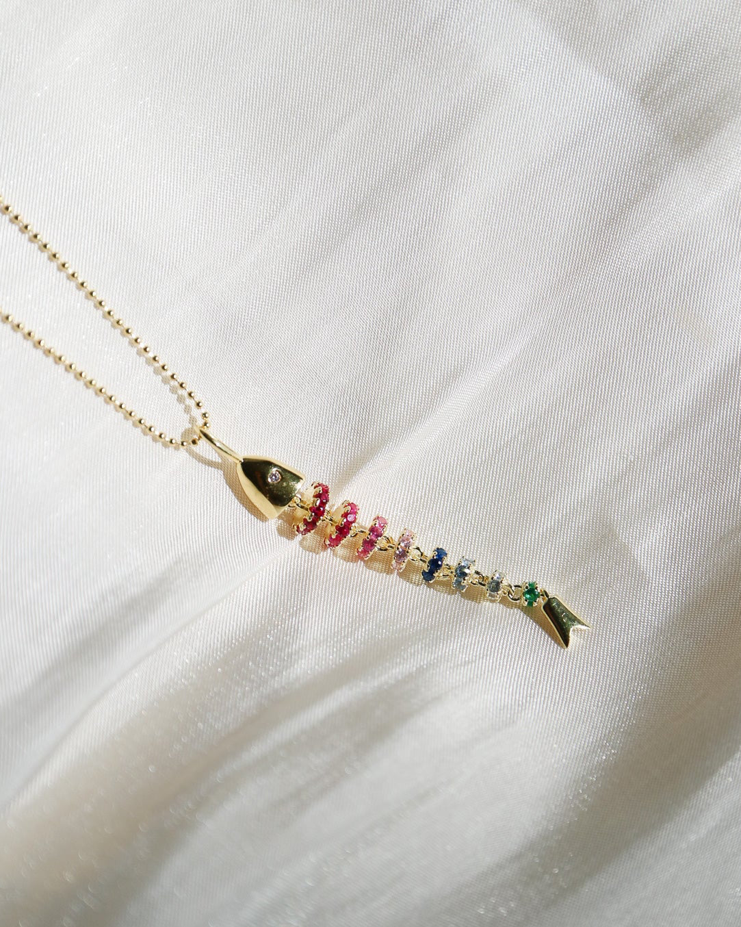 Necklace with a colorful pendant on a white fabric background