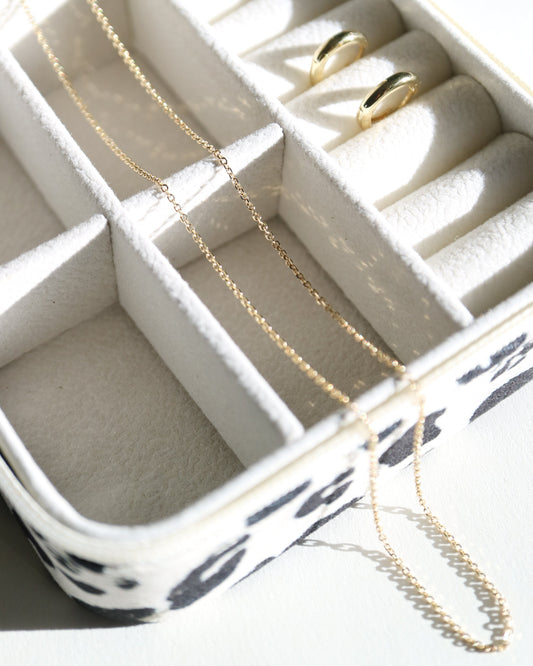 Jewelry organizer with gold necklaces and rings on a white surface