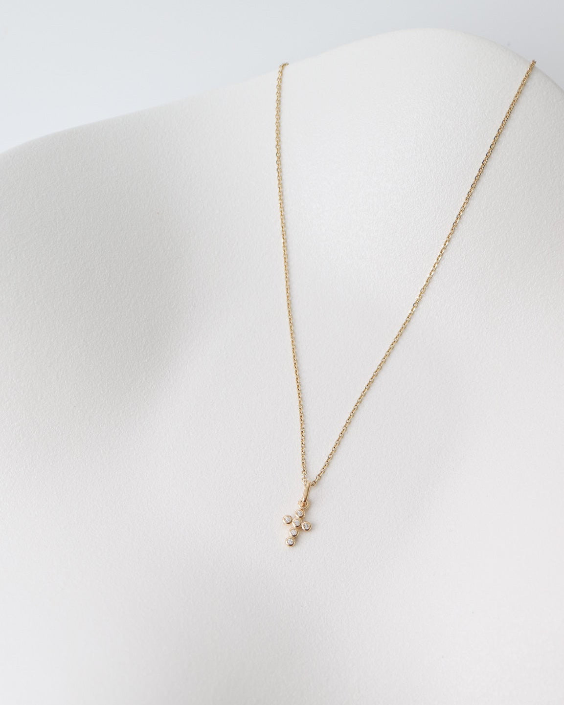 Gold necklace on a white mannequin bust against a white background