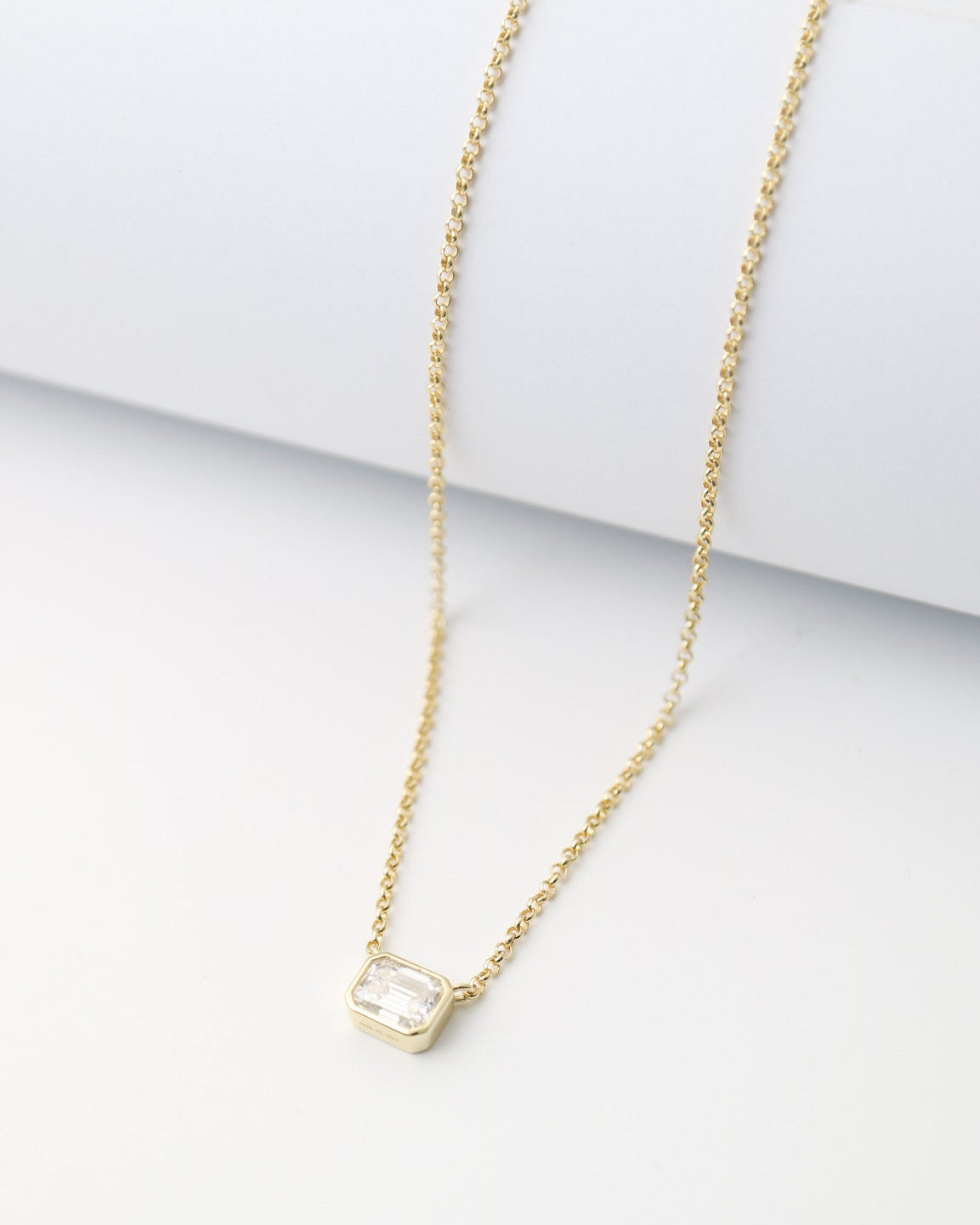 Gold necklace with a small pendant on a white surface
