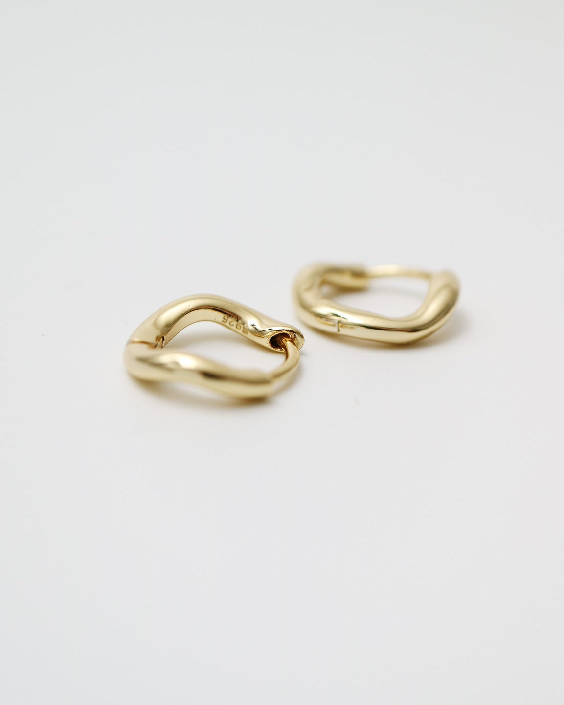 Gold heart-shaped earrings on a light gray background