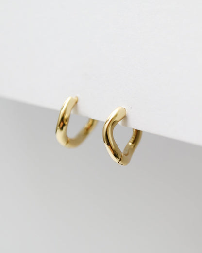 Gold hoop earrings on a light gray surface with a white background