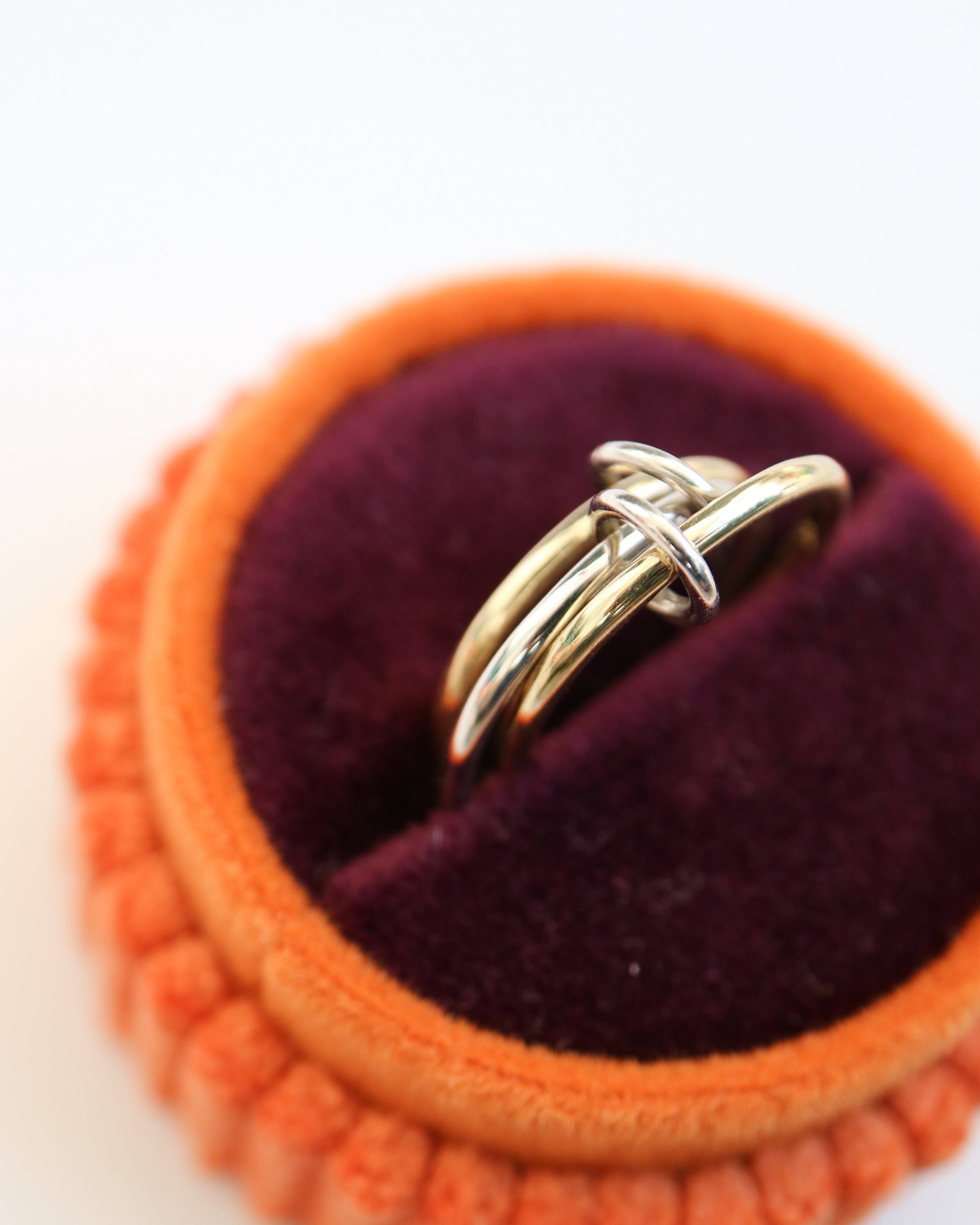 Gold ring in an orange and purple jewelry box on a white background
