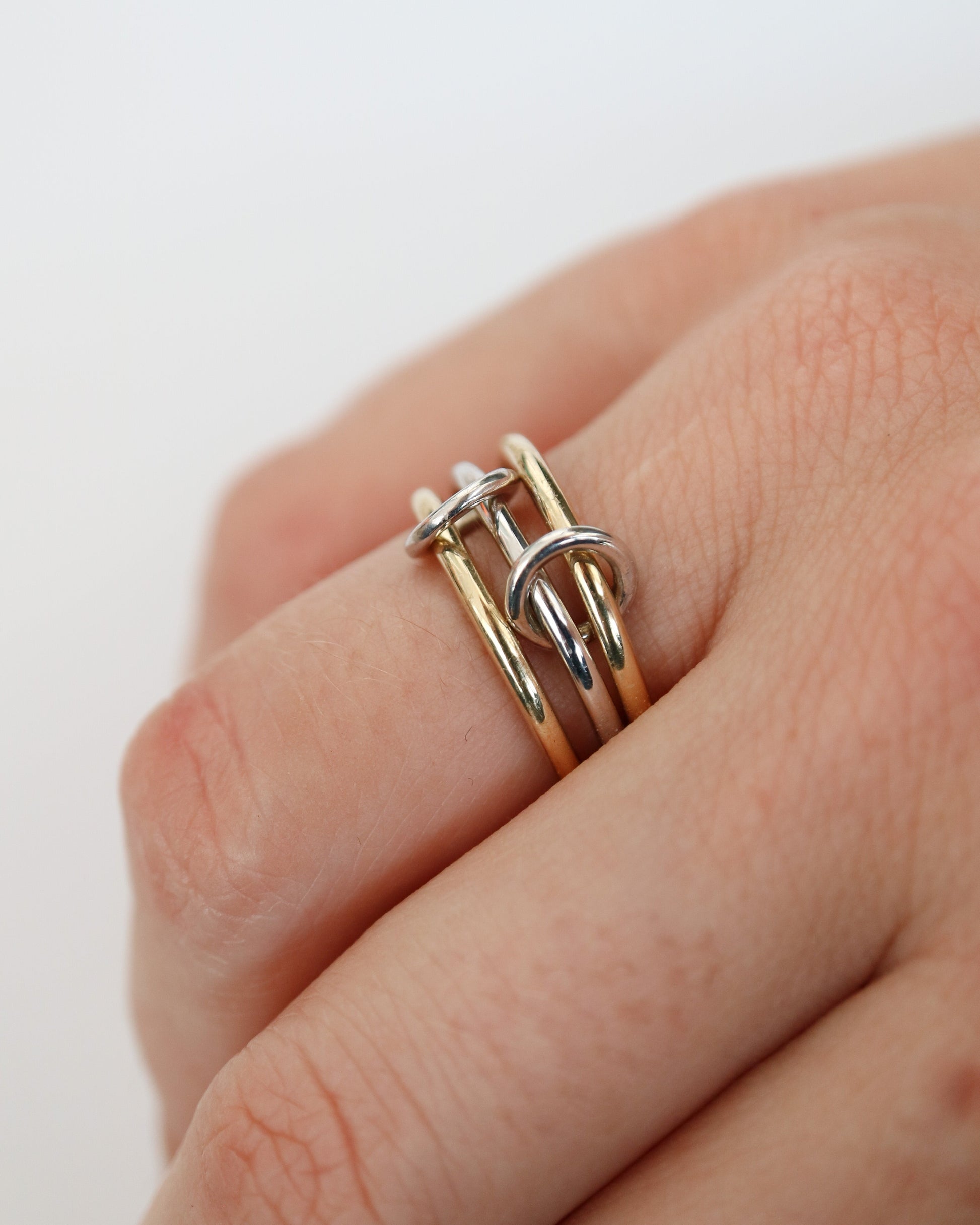 Close-up of a hand wearing three gold Russian rings on a white background