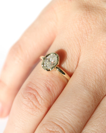 Gold ring with a large diamond on a person's finger against a white background