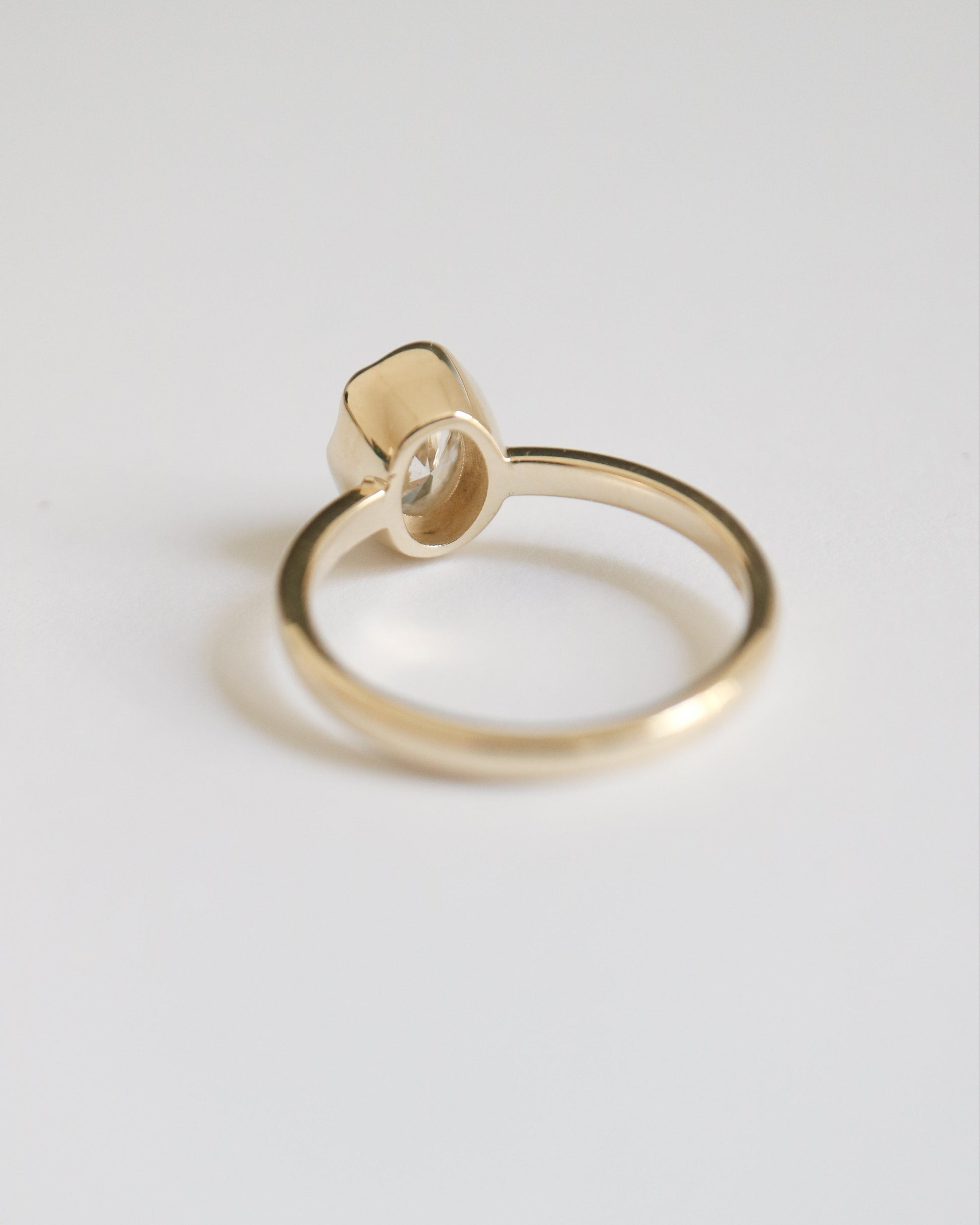 Gold ring with a small diamond on a light gray background