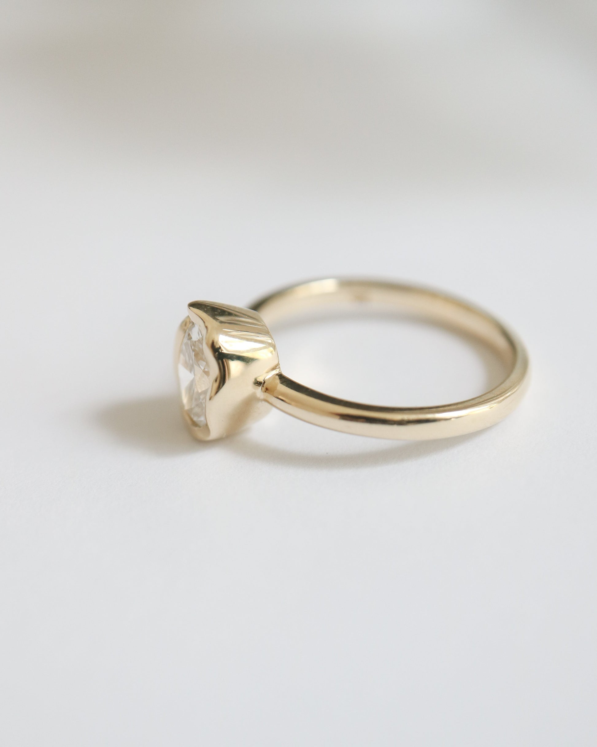Gold ring with a diamond on a light gray background