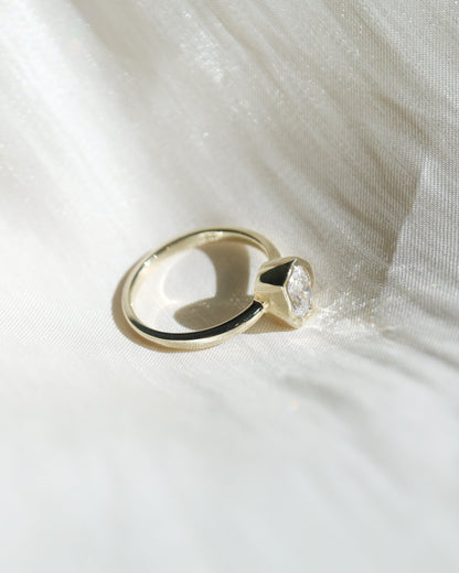 Gold ring with a unique design on a white fabric background