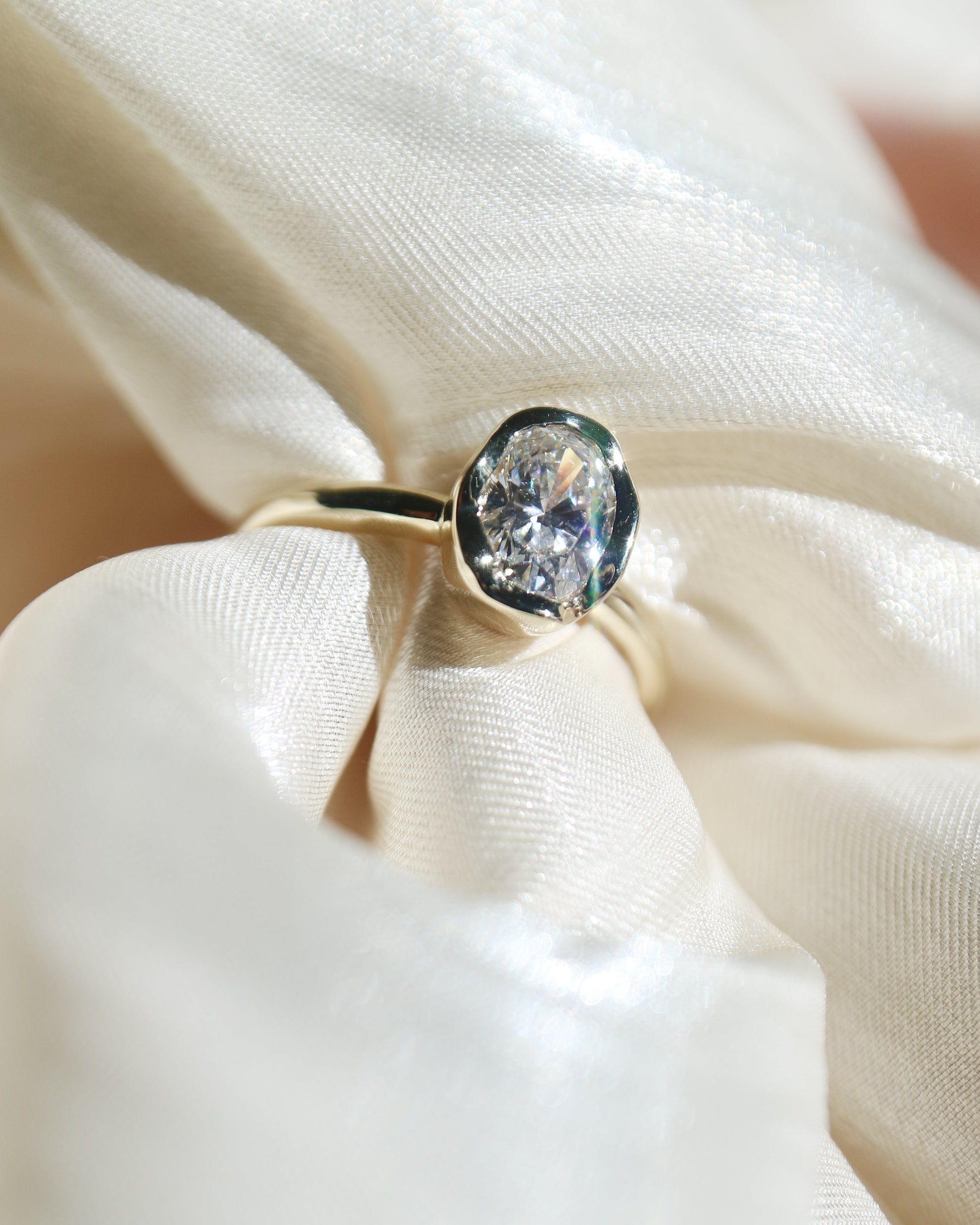 Gold ring with a large diamond on a white fabric background