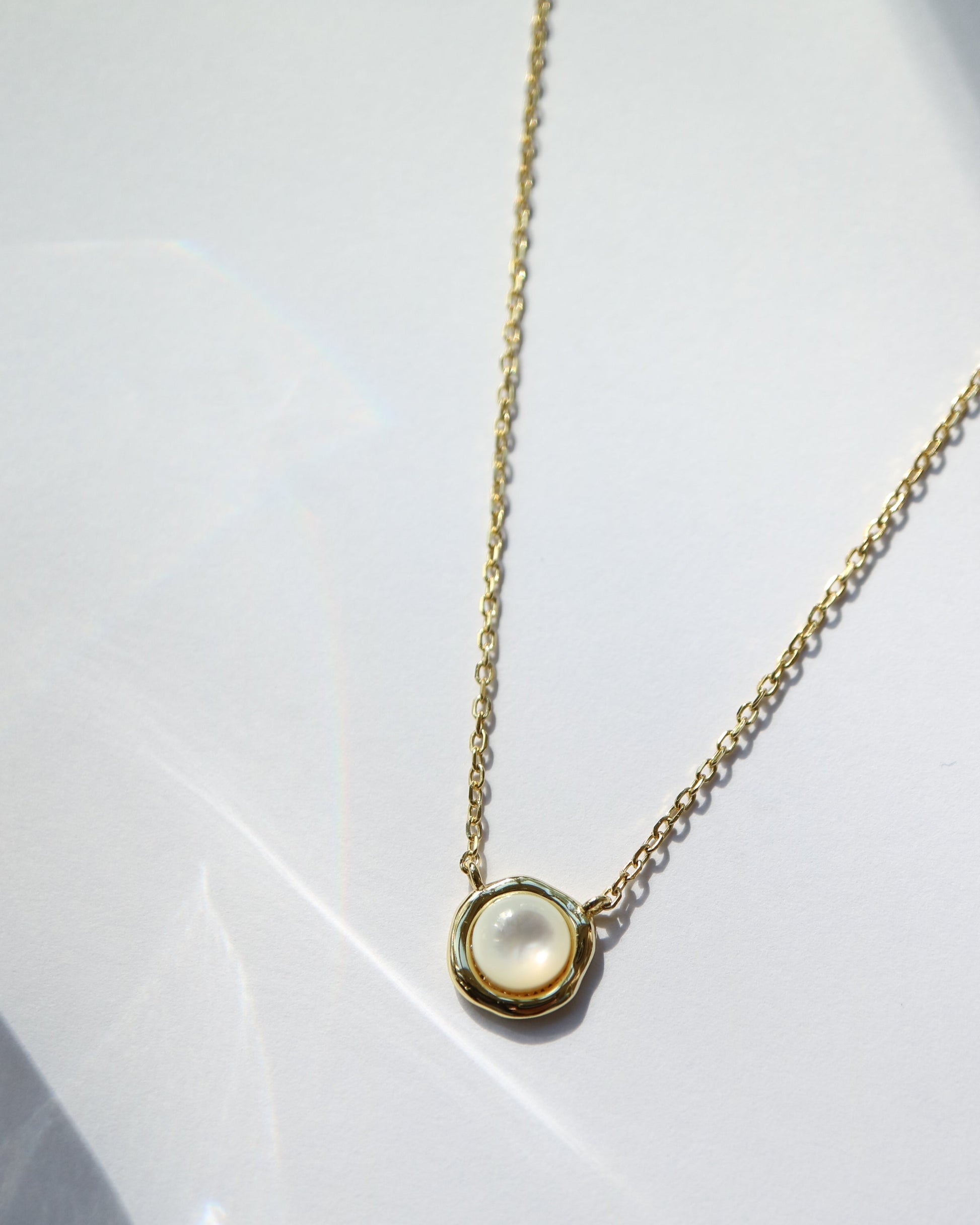 Gold necklace with a round pendant on a white background