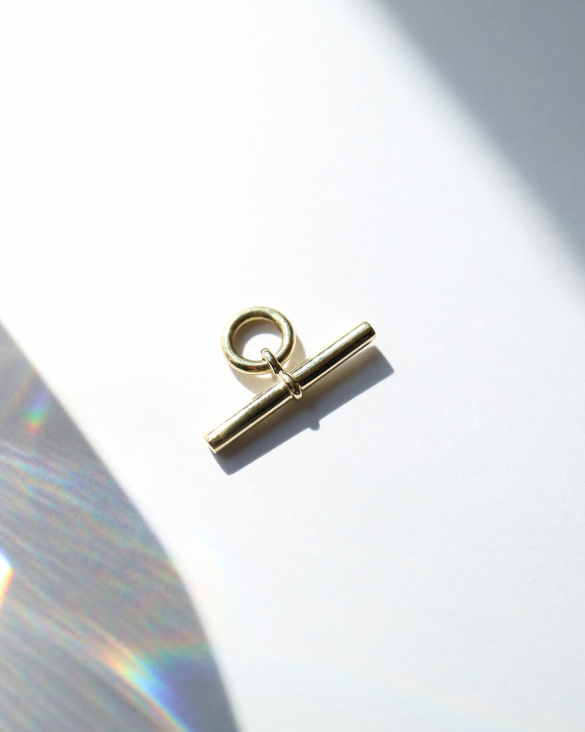 Gold toggle clasp on a white background with a soft shadow