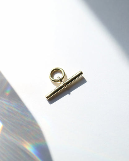 Gold toggle clasp on a white background with a soft shadow