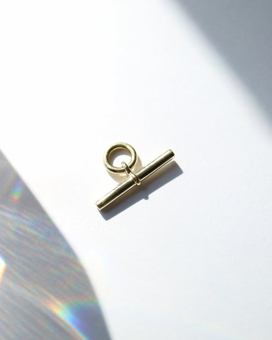 Gold toggle clasp on a white background with a soft shadow