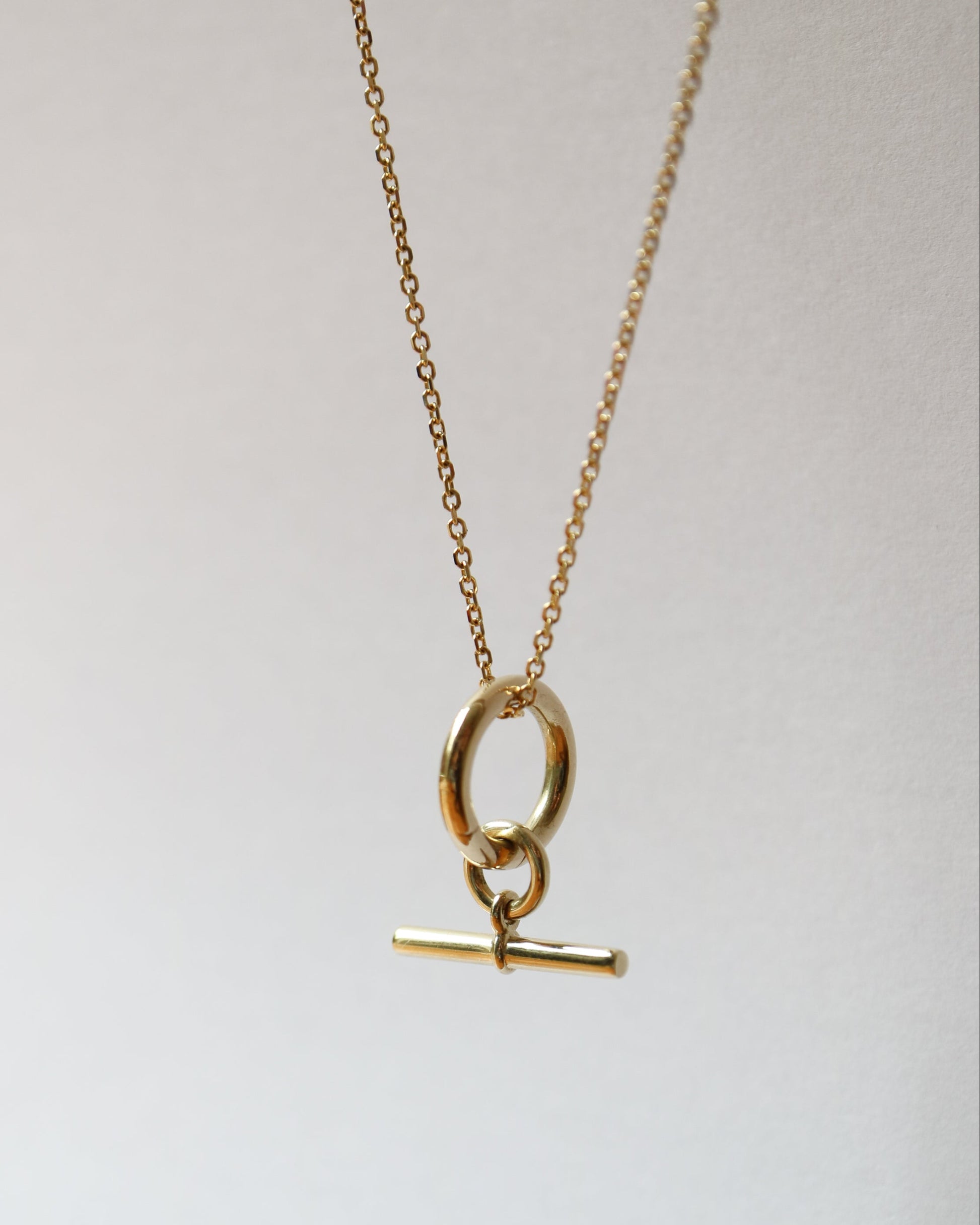 Gold necklace with a pendant on a light gray background