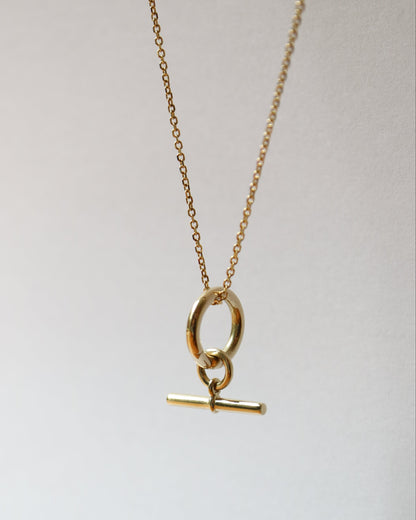 Gold necklace with a pendant on a light gray background
