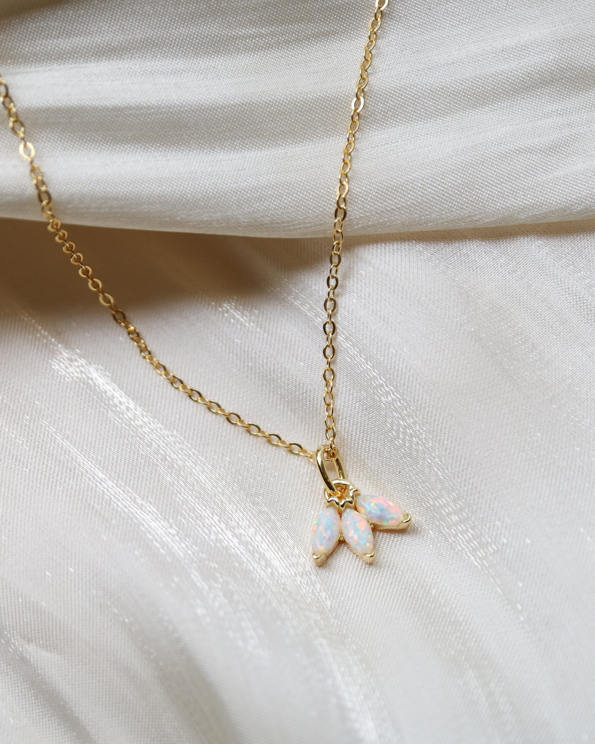 Gold necklace with a small pendant on a white fabric background