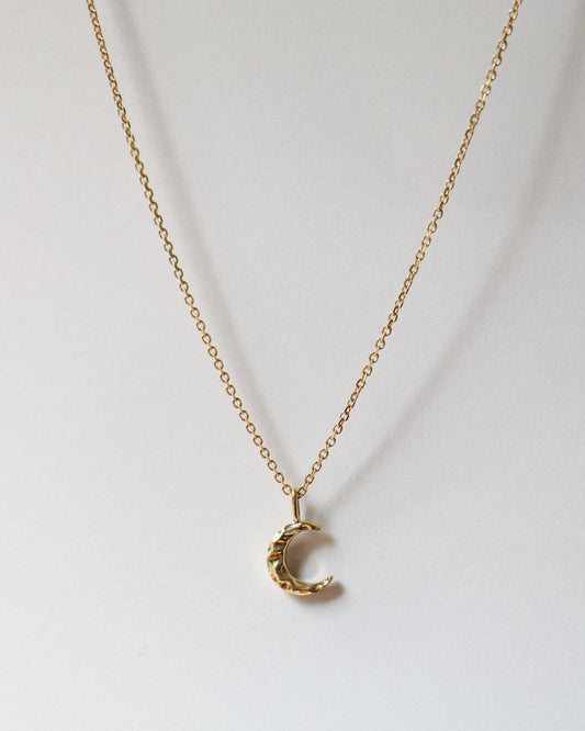 Gold necklace with a crescent moon pendant on a white background
