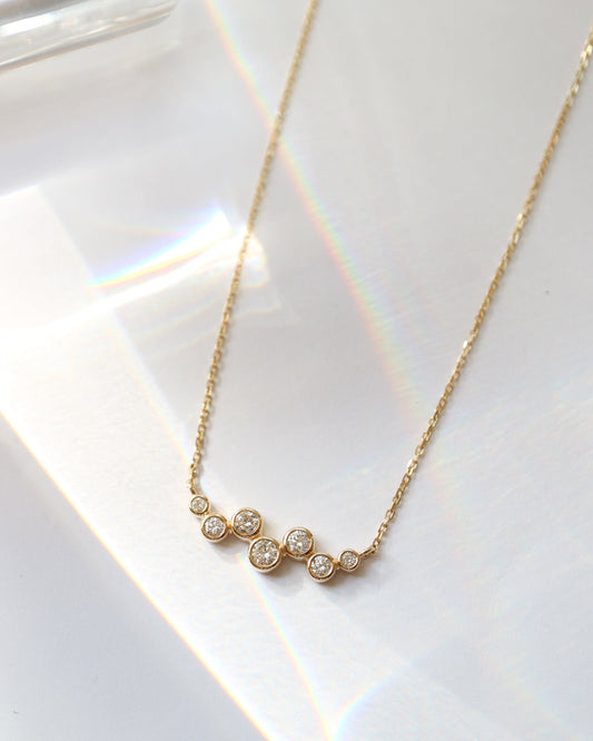 Gold necklace with small diamonds on a white surface
