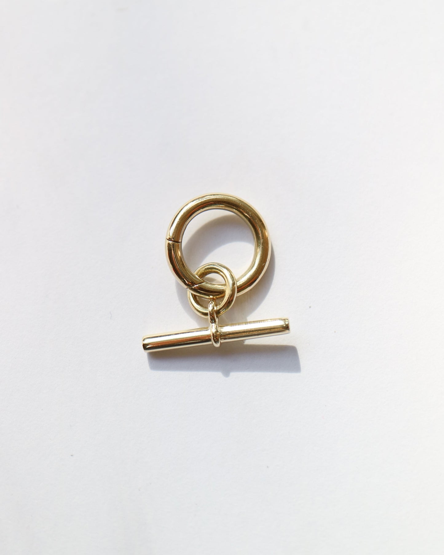 Gold charm with a toggle clasp on a white background
