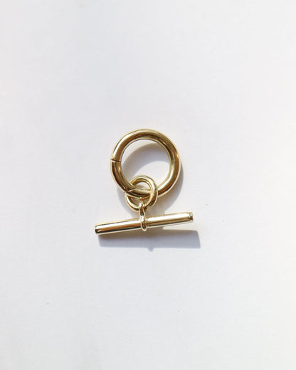 Gold charm with a toggle clasp on a white background