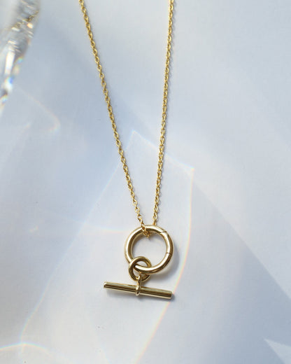 Gold necklace with a round pendant on a white background