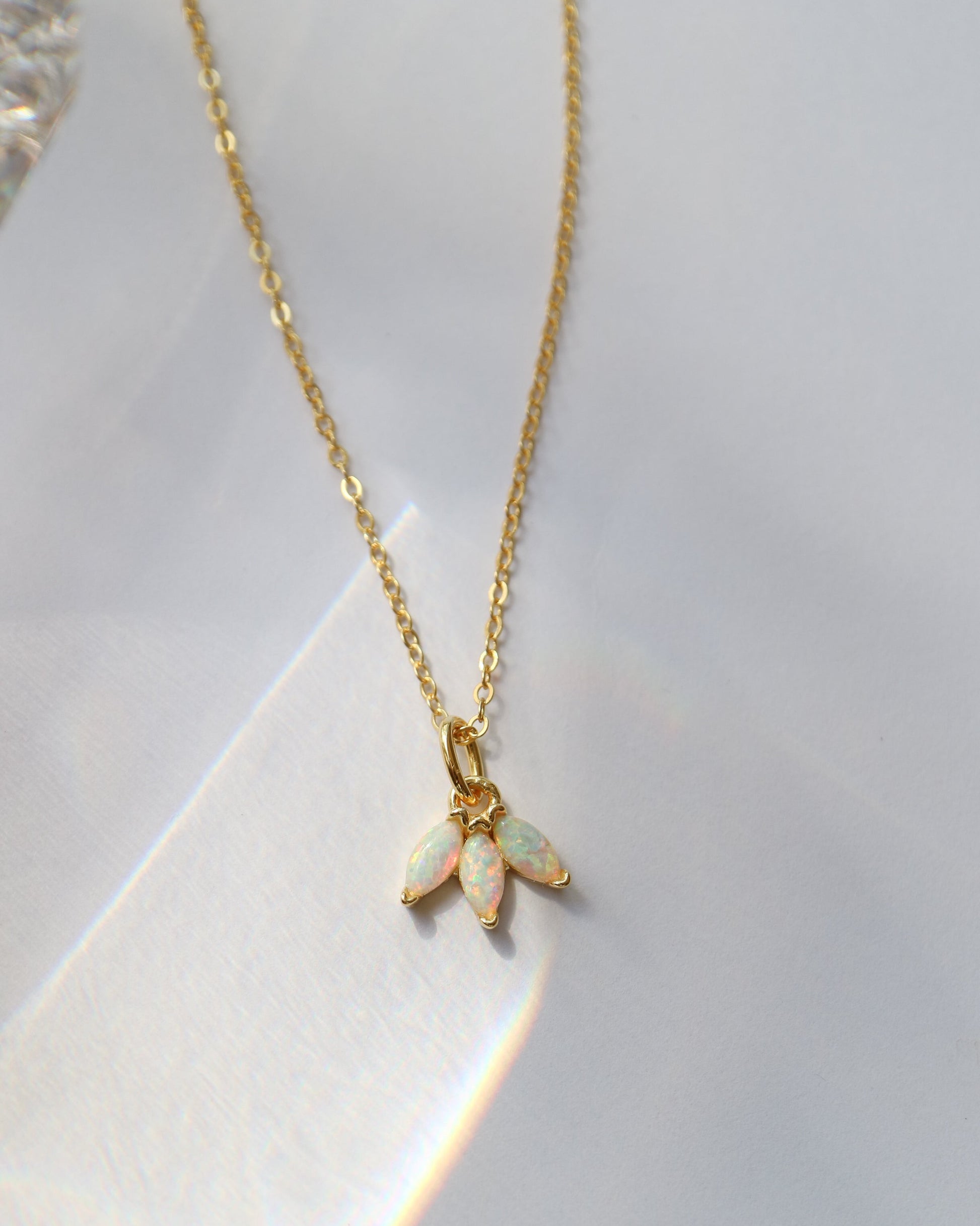 Gold necklace with an opal pendant on a white background