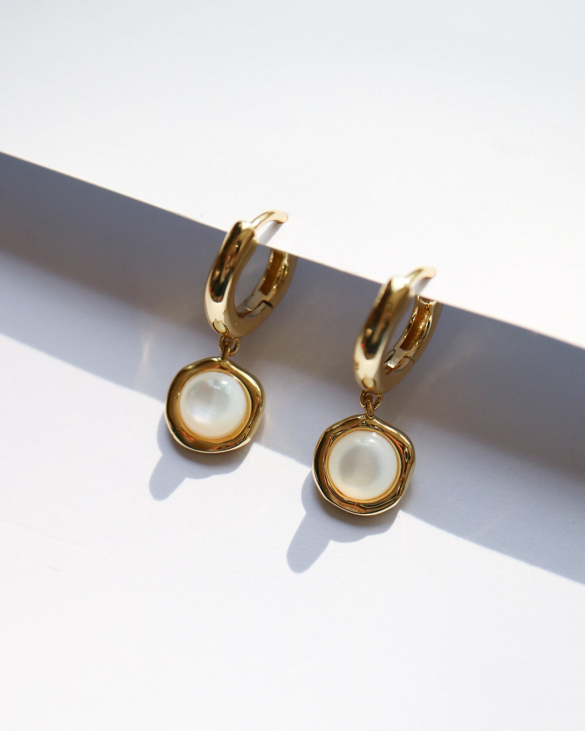 Gold hoop earrings with pearl-like centers on a white background