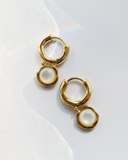 Gold hoop earrings with pearl-like stones on a white background