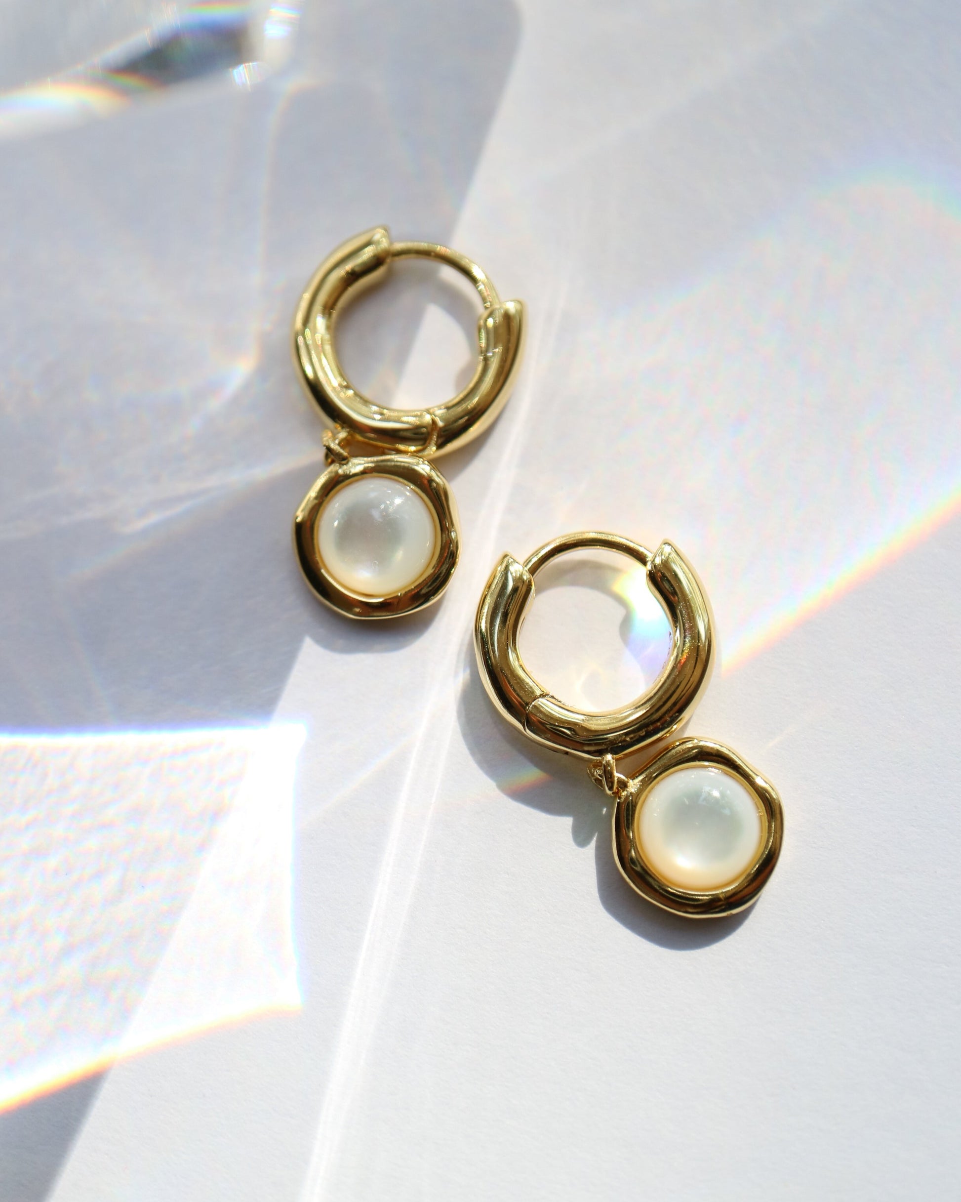 Gold hoop earrings with a central gemstone on a white background