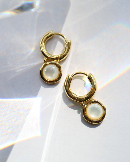 Gold hoop earrings with a central gemstone on a white background