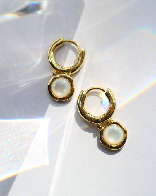 Gold hoop earrings with a central gemstone on a white background