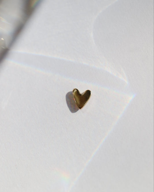 Gold heart-shaped earring on a white background