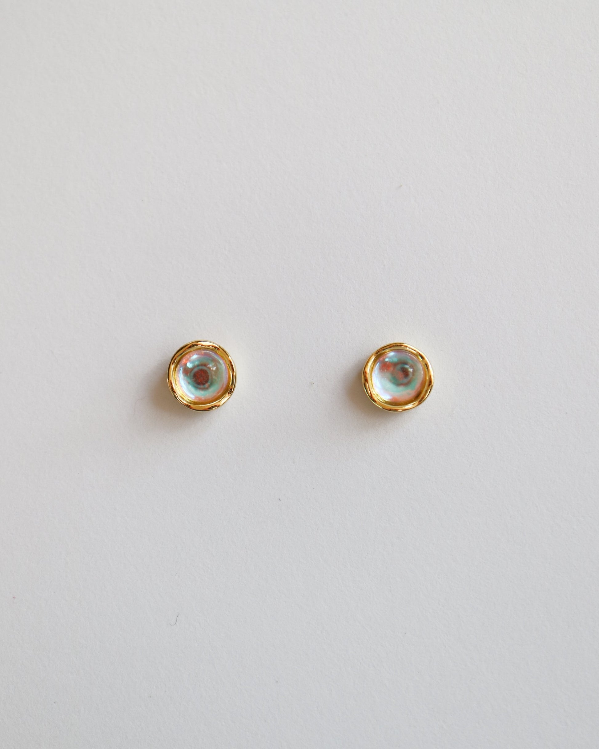 Pair of gold stud earrings on a light gray background