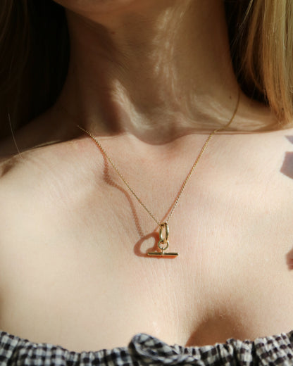 Close-up of a person wearing a gold necklace with a heart-shaped pendant.