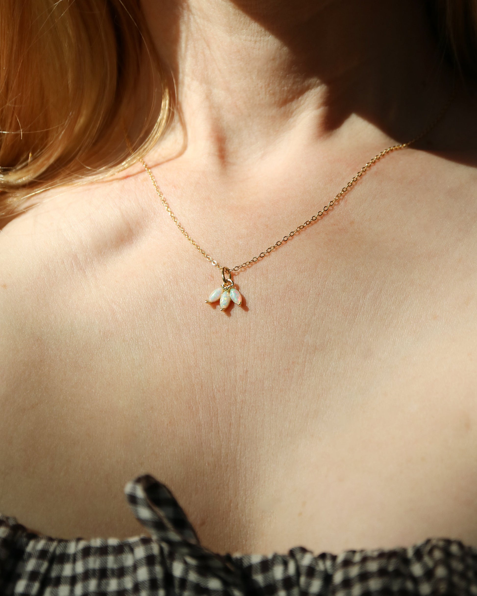 Close-up of a necklace with a pendant on a person wearing a black and white checkered top.
