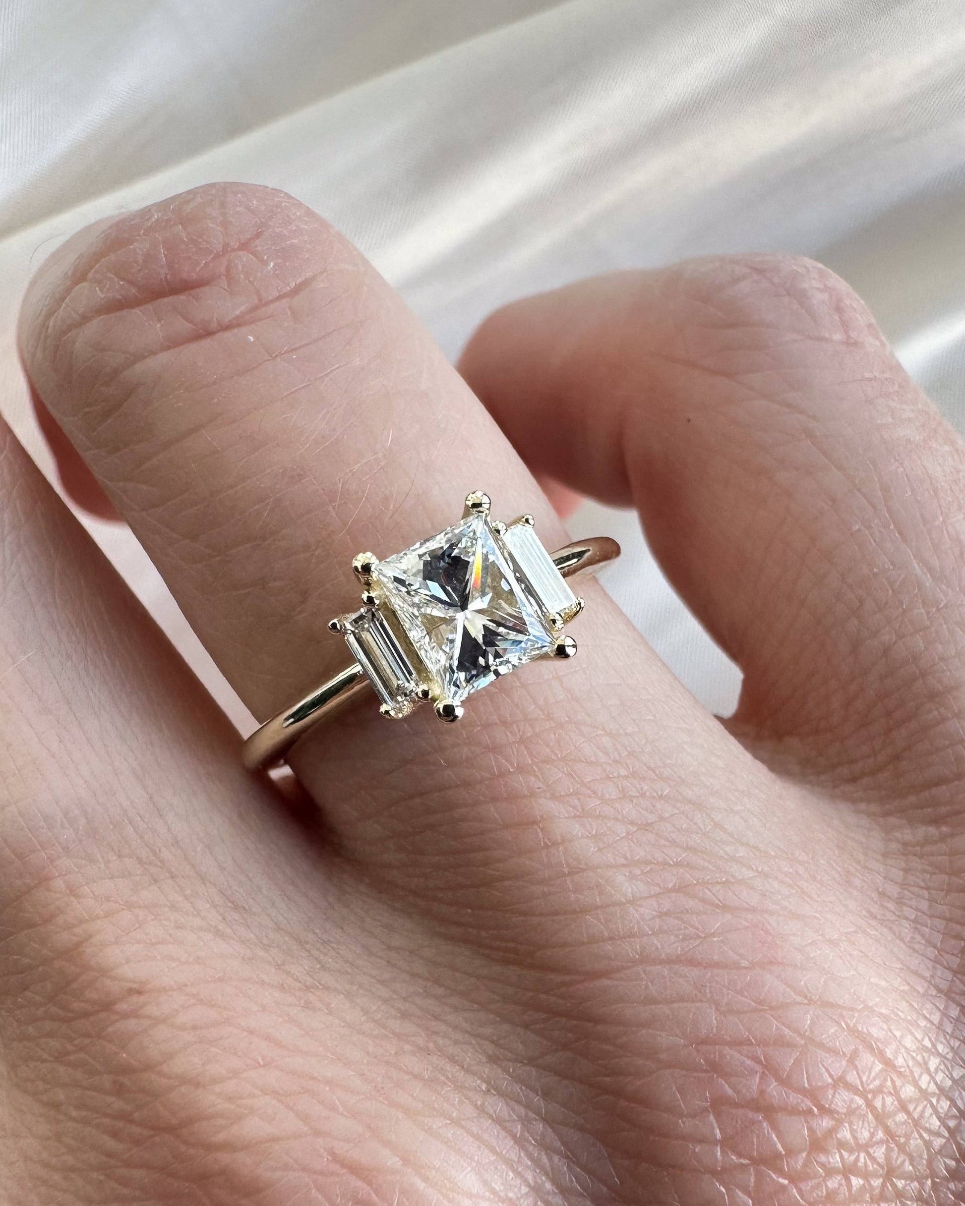 Gold ring with a diamond on a hand against a white background