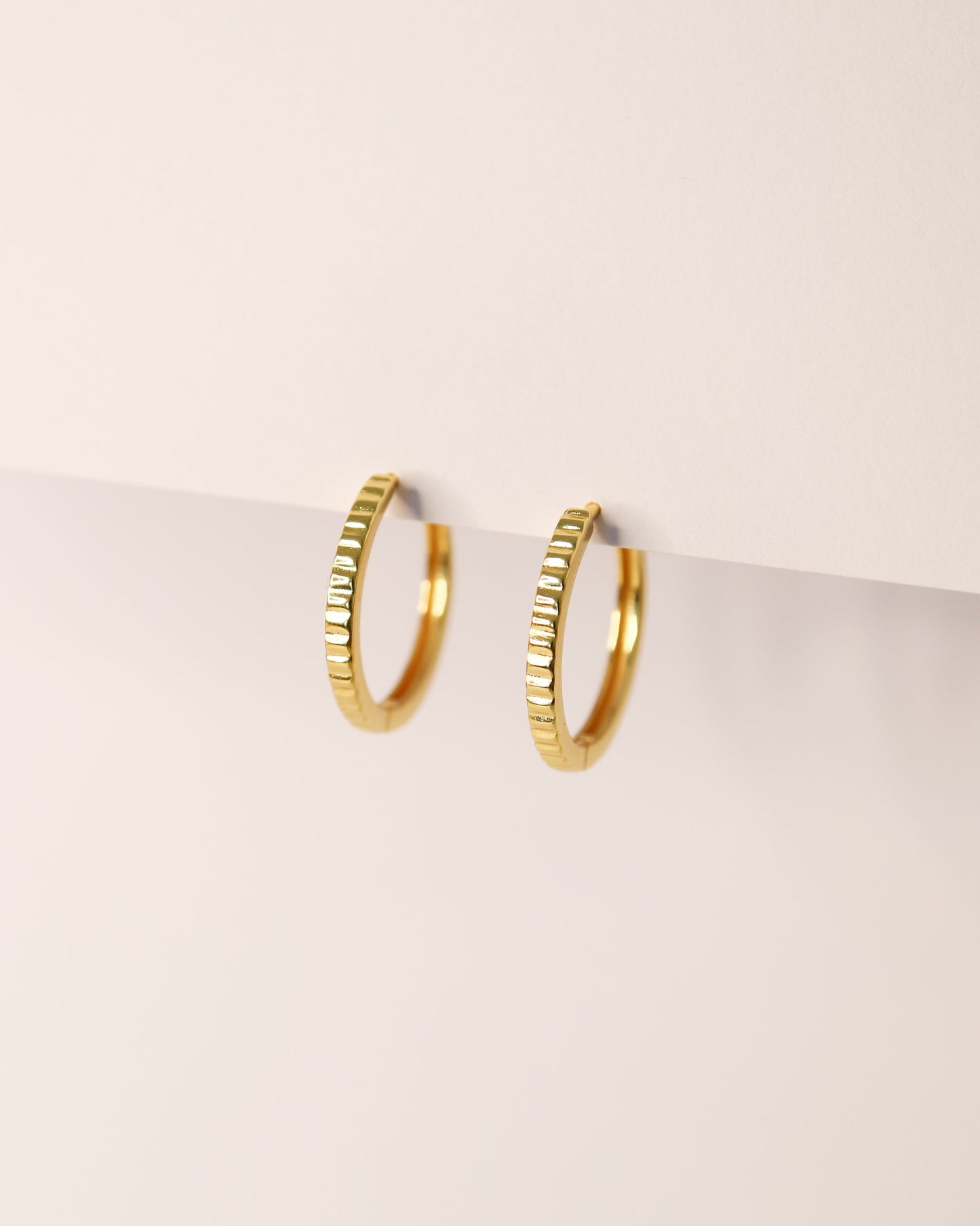 Gold hoop earrings on a light beige background