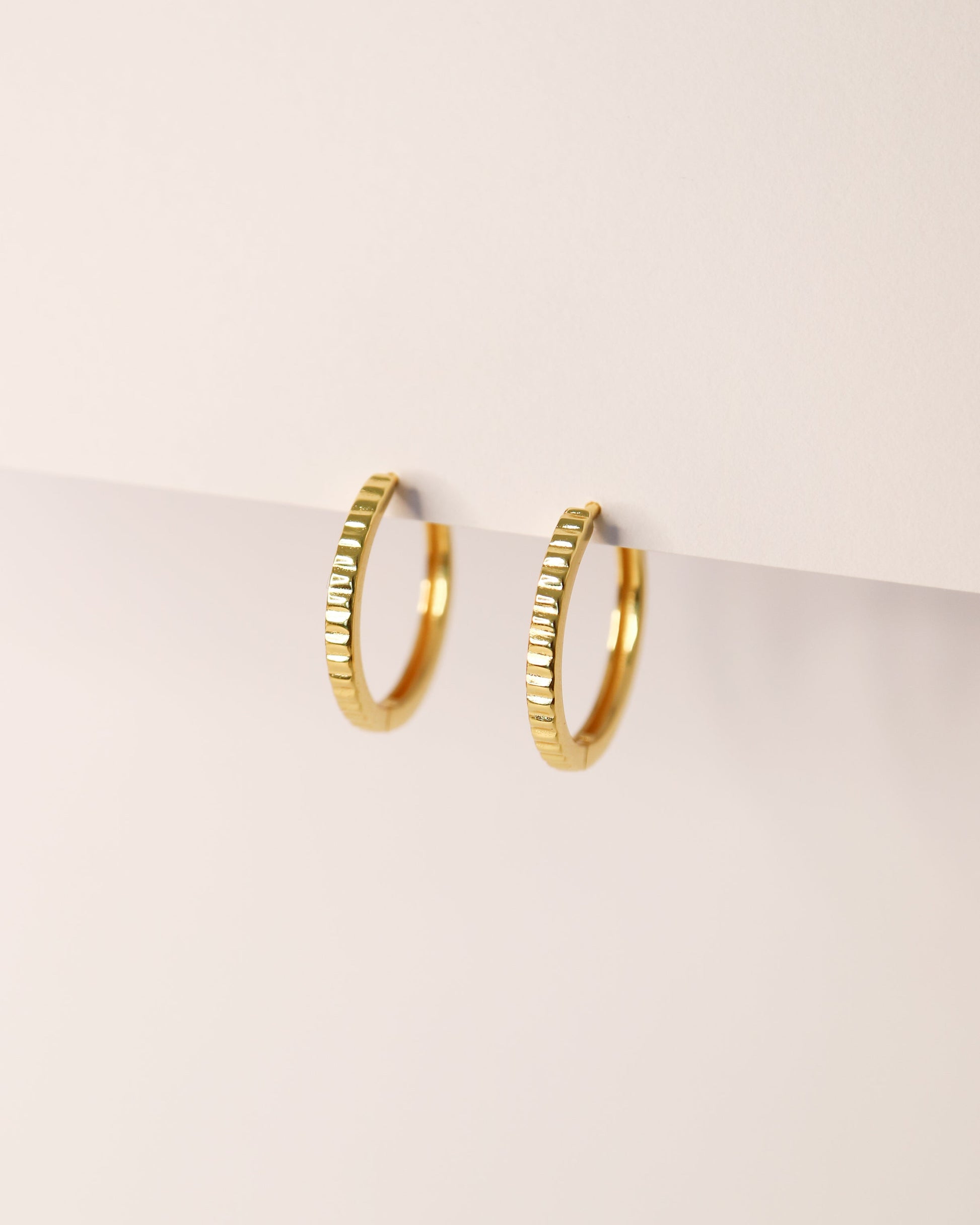 Gold hoop earrings on a light beige background