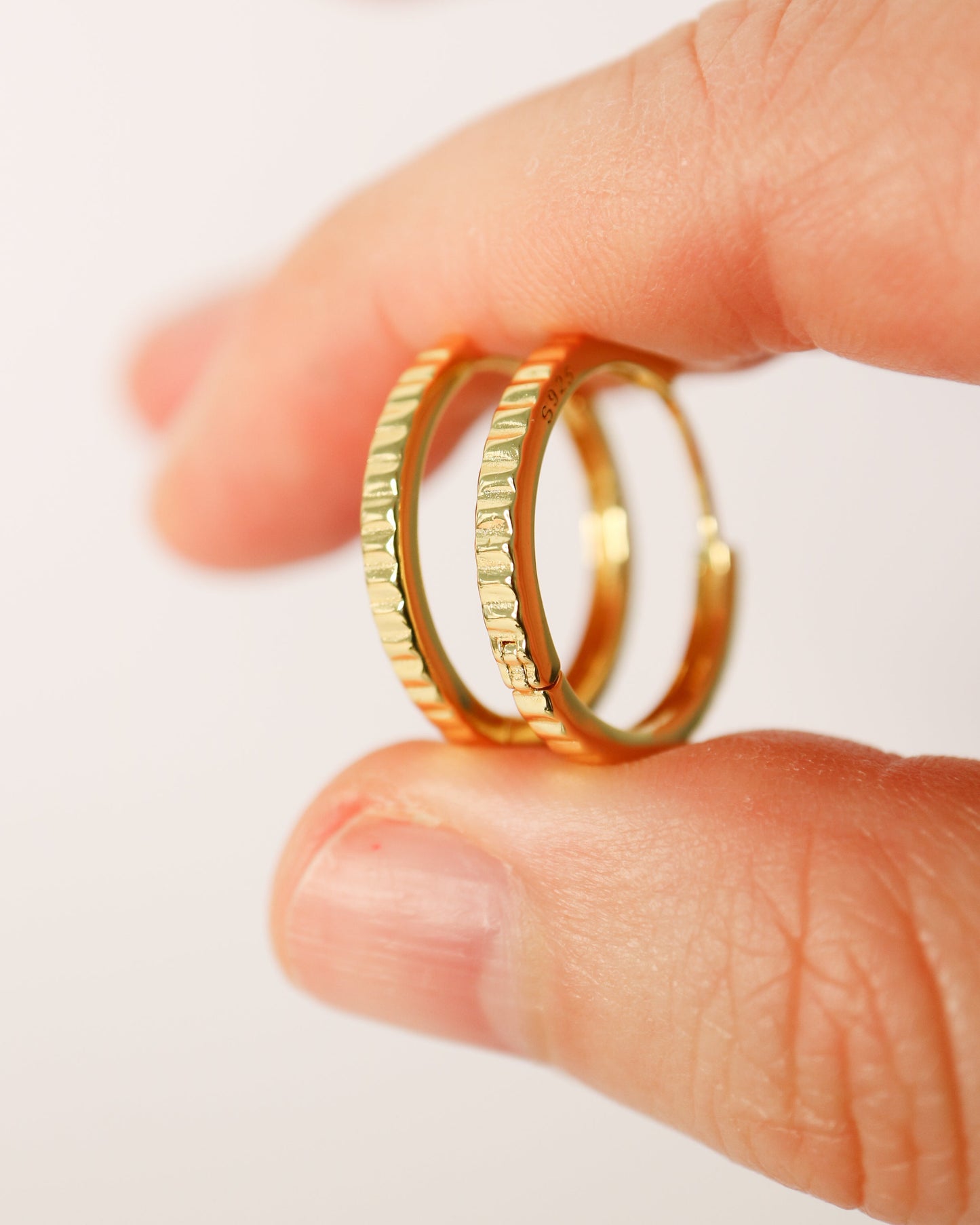 Gold rings on a finger against a white background