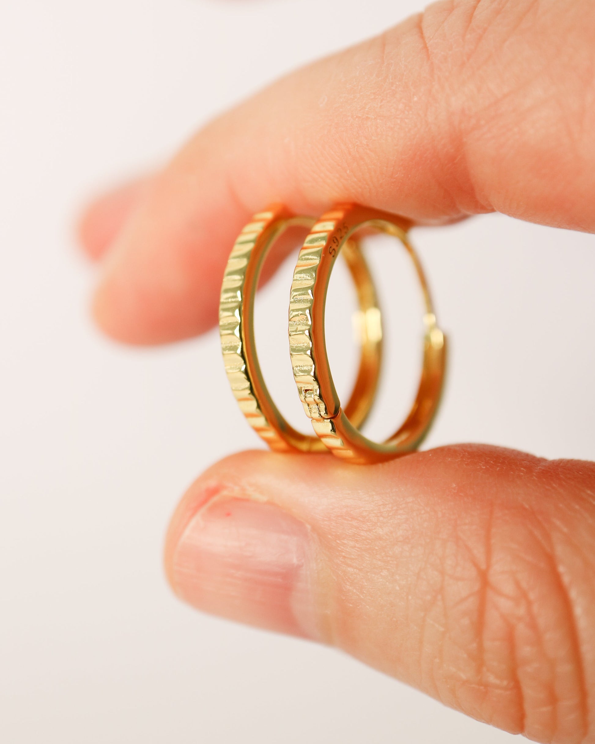 Gold rings on a finger against a white background