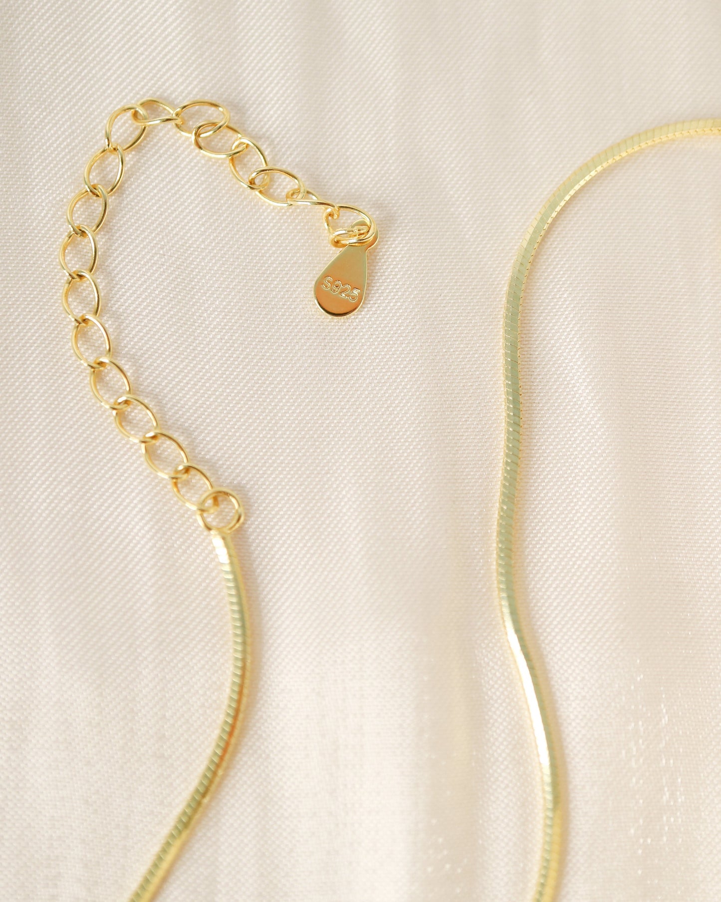 Gold necklace on a beige fabric background