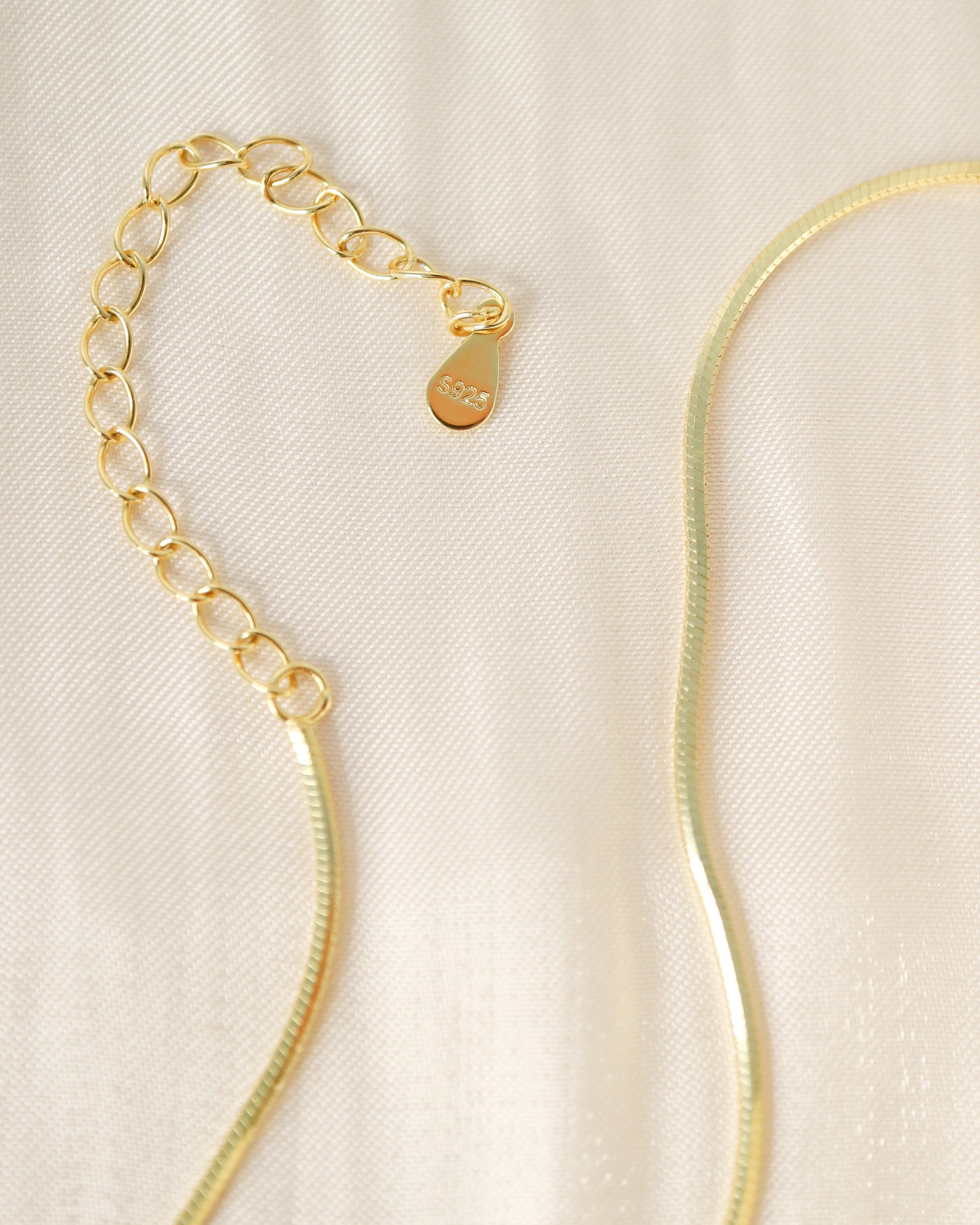 Gold necklace on a beige fabric background