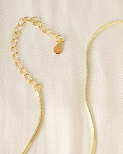 Gold necklace on a beige fabric background