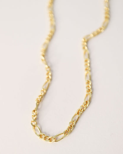 Gold chain necklace on a light gray background
