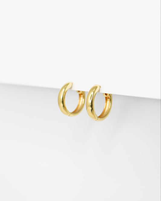Gold hoop earrings on a white surface