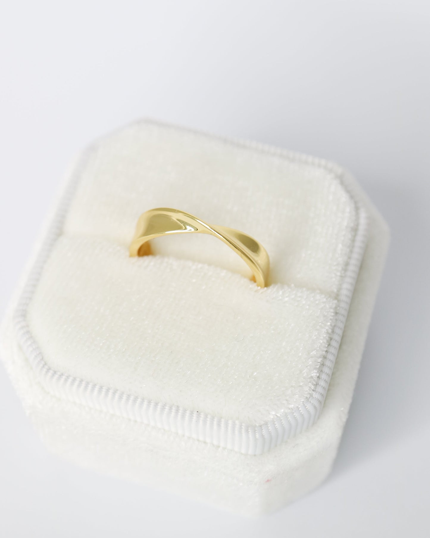 Gold ring on a white cushion with a white background